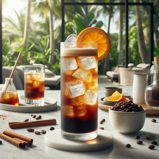 Espresso-Tonic, gefüllt mit Eiswürfeln, einer goldbraunen Schicht von Espresso Karibik von TeeBohne Einbeck und spritzigem Tonic Water, garniert mit einer frischen Orangenscheibe und einem Hauch Zimt